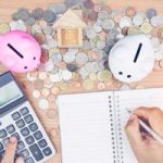 finger  pressing calculator, writing in notebook, piggybanks, coins